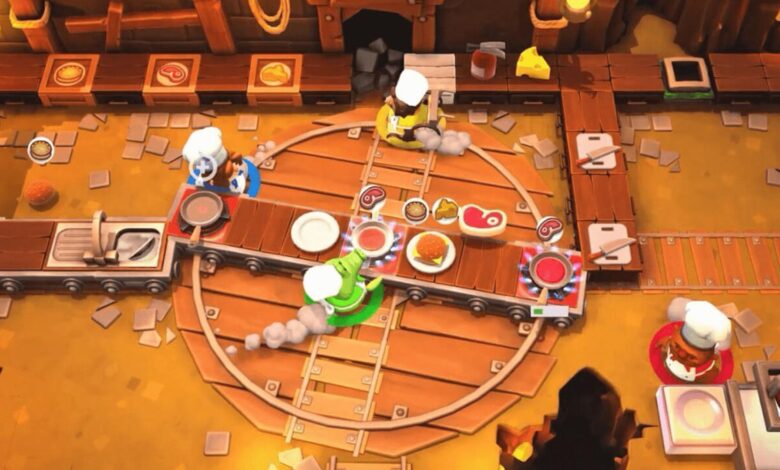 Cena do jogo Overcooked! mostra quatro personagens vestidos de chefs preparando pratos em uma cozinha caótica com esteiras e fogões.